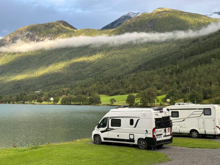 Idyllic mountain landscape with camper vans by a tranquil lake, perfect for outdoor adventures.